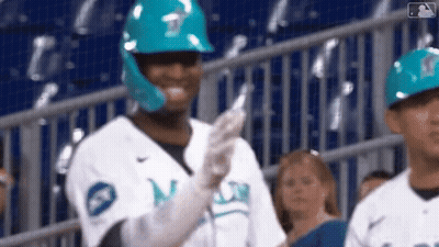 A Baseball Player Wearing A Blue Helmet And Gloves Is Standing In The Stands . GIF