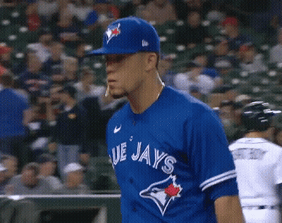 A Baseball Player Wearing A Blue Jays Uniform Is Standing In The Outfield . GIF