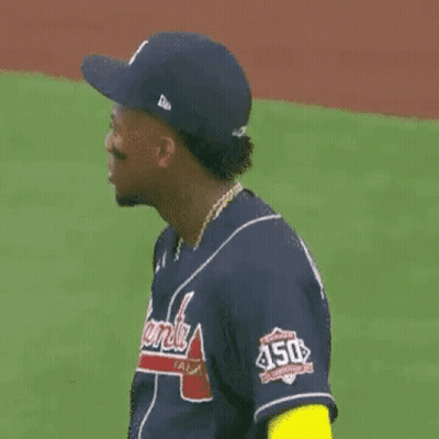 a baseball player wearing a blue jersey and a hat is standing on a field .