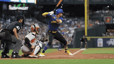 A Baseball Player Wearing A Blue Sea Jersey Swings His Bat GIF