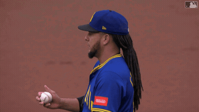 A Baseball Player Wearing A Blue Seattle Jersey Adjusts His Hat GIF
