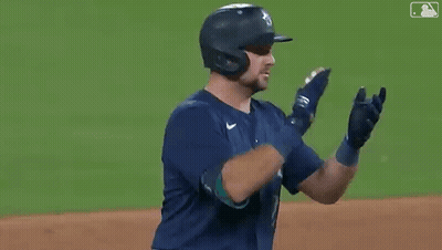 A Baseball Player Wearing A Helmet And Gloves Is Clapping His Hands On The Field . GIF