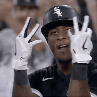 A Baseball Player Wearing A Helmet And Gloves Is Giving The Peace Sign . GIF