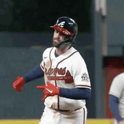 A Baseball Player Wearing A Helmet And Gloves Is Pointing At Something While Running On The Field . GIF