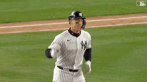 A Baseball Player Wearing A Helmet And Gloves Is Saluting The Crowd . GIF