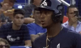 A Baseball Player Wearing A Helmet Stands In A Crowd Of People GIF