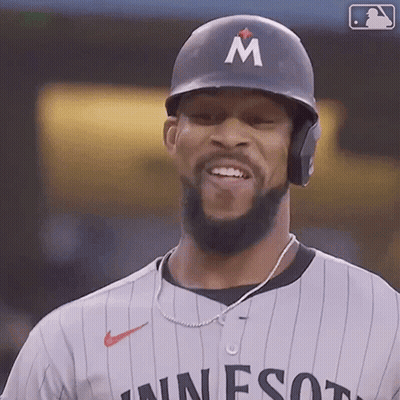 A Baseball Player Wearing A Helmet With The Letter M On It Is Smiling GIF