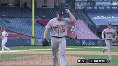 A Baseball Player Wearing A Houston Jersey Is Throwing A Ball While Another Player Runs Behind Him . GIF