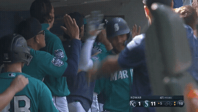 A Baseball Player Wearing A Mariner Jersey High Fives His Teammates In The Dugout GIF