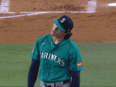 A Baseball Player Wearing A Mariner 'S Jersey Holds His Arms In The Air GIF