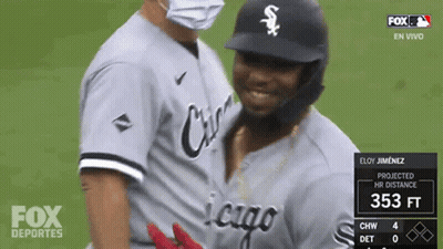 A Baseball Player Wearing A Mask Is Being Hugged By Another Player GIF