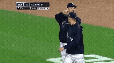 A Baseball Player Wearing A New York Yankees Hat Is Smoking A Cigarette In Front Of A Crowd . GIF