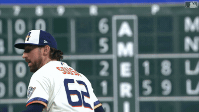 A Baseball Player Wearing A Number 62 Jersey Stands In Front Of A Scoreboard GIF