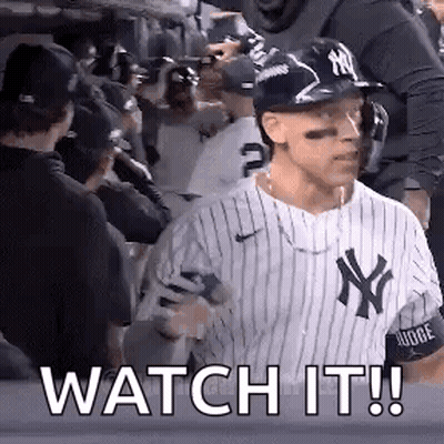 A Baseball Player Wearing A Ny Yankees Uniform Is Standing In Front Of A Crowd Of People . GIF