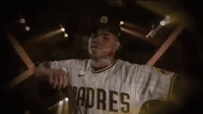 A Baseball Player Wearing A Padres Jersey And Hat Is Standing In Front Of A Stage . GIF
