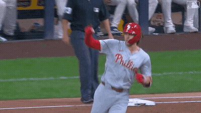 A Baseball Player Wearing A Phillies Jersey Is Running Towards Home Plate . GIF