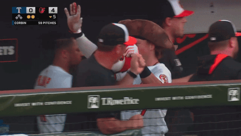 A Baseball Player Wearing A Pirate Hat High Fives Another Player In A Dugout GIF