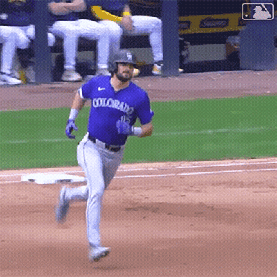 A Baseball Player Wearing A Purple Colorado Jersey Is Running To First Base . GIF