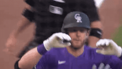 A Baseball Player Wearing A Purple Jersey And A Black Helmet Is Being Hugged By His Teammates . GIF
