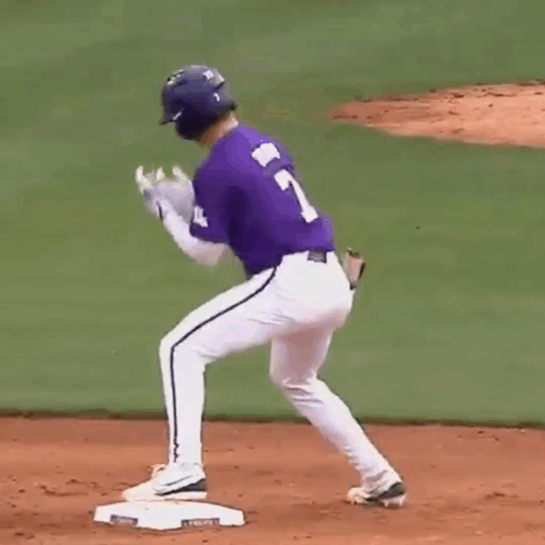 A Baseball Player Wearing A Purple Jersey With The Number 7 On It Is Standing On The Base . GIF