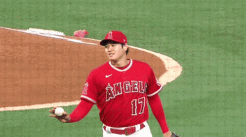 A Baseball Player Wearing A Red Angels Jersey Is Shaking Hands With Another Player GIF