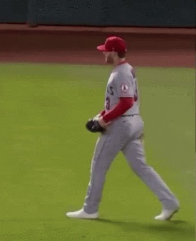 A Baseball Player Wearing A Red Hat And White Pants Is Running On A Baseball Field . GIF