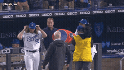 A Baseball Player Wearing A Royals Uniform Is Being Escorted By A Man In A Yellow Jacket GIF