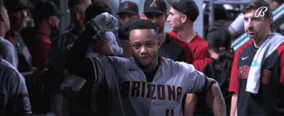 a baseball player wearing an arizona jersey stands in a locker room