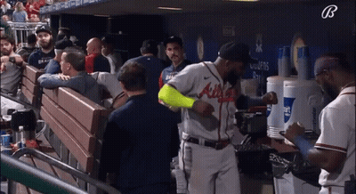 A Baseball Player Wearing An Atlanta Braves Jersey Stands In A Dugout GIF