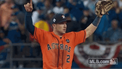 A Baseball Player Wearing An Orange Astros Jersey Holds His Glove Up In The Air GIF