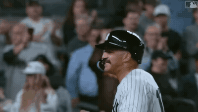 A Baseball Player With A Mustache Wearing A Helmet Stands In Front Of A Crowd Of People . GIF