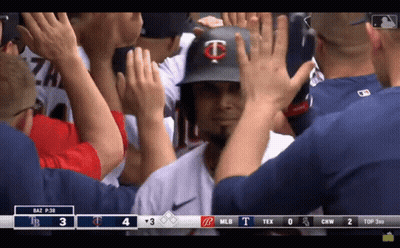 A Baseball Player With The Letter T On His Helmet Is Being High Fived By His Teammates GIF