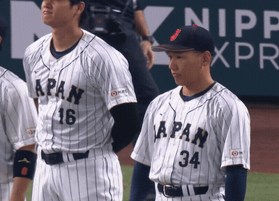 A Baseball Player With The Number 34 On His Jersey Stands Next To Another Player GIF
