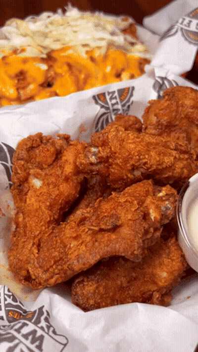 A Basket Of Fried Chicken Wings Sits On A Table GIF