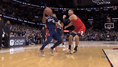A Basketball Game Being Played In Front Of A Caesars Sportsbook Banner GIF