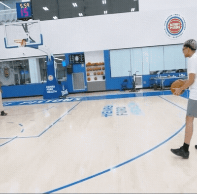 A Basketball Game Is Being Played In A Gym With A Scoreboard Above The Basketball Hoop That Says 5-5 GIF