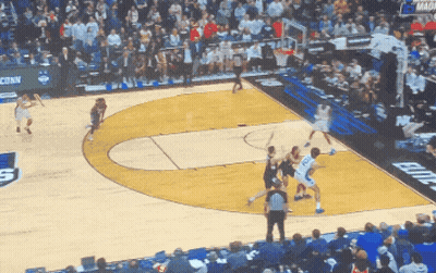 A Basketball Game Is Being Played In Front Of A Crowd With A Banner That Says Conn On It GIF