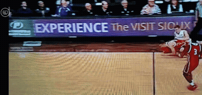 A Basketball Game Is Being Played In Front Of A Sign That Says " Experience The Visit Sioux " GIF