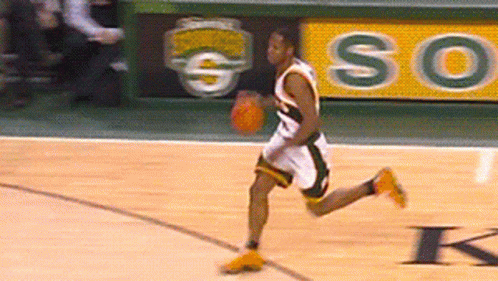 A Basketball Player Dribbles A Ball On A Court With A So Sign Behind Him GIF