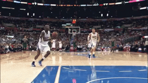 A Basketball Player Dribbles The Ball While Another Player Tries To Block His Shot GIF