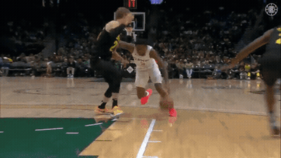 A Basketball Player Dribbles The Ball While Another Player Tries To Stop Him . GIF