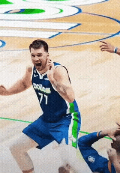 A Basketball Player In A Blue And Green Uniform Is Jumping In The Air On A Court . GIF