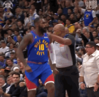 A Basketball Player In A Blue Jersey With The Number 10 On It Is Standing In Front Of A Crowd Of People . GIF