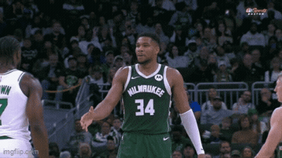 A Basketball Player In A Milwaukee Jersey Is Shaking Hands With Another Player . GIF