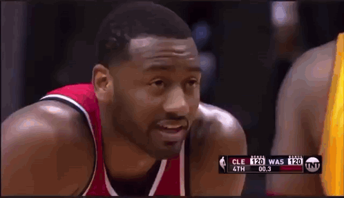 A Basketball Player In A Red And Black Jersey Is Looking At The Camera During A Game GIF