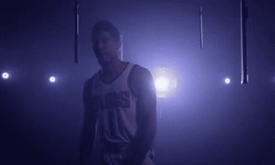 A Basketball Player In A Suns Jersey Is Standing In A Dark Room . GIF