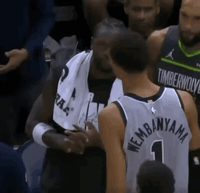 A Basketball Player In A Timberwolves Jersey Is Talking To Another Player In A Crowd . GIF