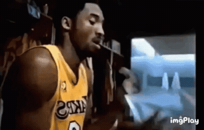 A Basketball Player In A Yellow Jersey Is Smoking A Cigarette In Front Of A Tv . GIF