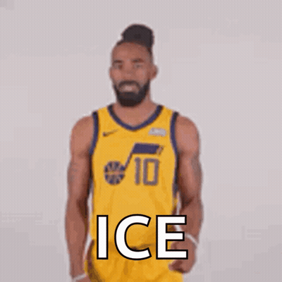 A Basketball Player In A Yellow Jersey Is Standing In Front Of A White Wall . GIF