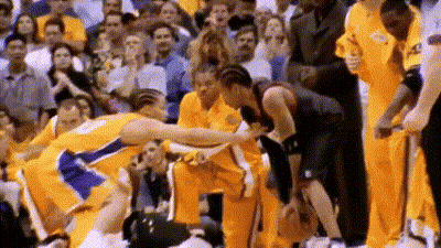 A Basketball Player Is Being Helped Off The Court By A Teammate While A Crowd Watches . GIF